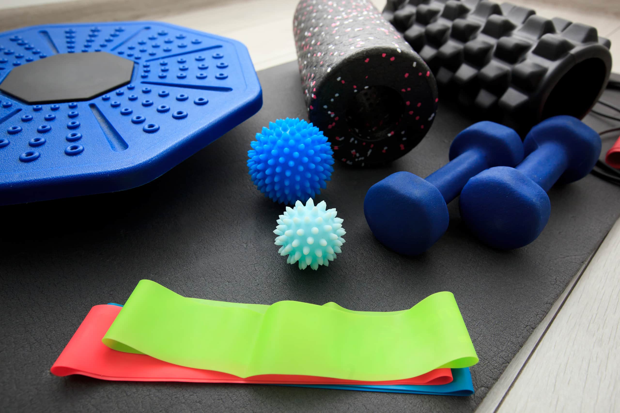 Terabänder, Trainingsbälle, Hanteln und Faszienrolle auf einer Übungsmatte.